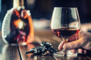 Cup cognac or brandy hand man the keys to the car and irresponsible driver.
